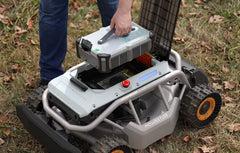Mowrator robotic mower with battery pack being installed by person on grass