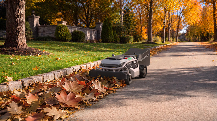 MOWRATOR robotic leaf vacuum clearing autumn leaves along a driveway curb