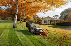 Mowrator tow-behind lawn sweeper efficiently clearing dry leaves on a large flat grass lawn