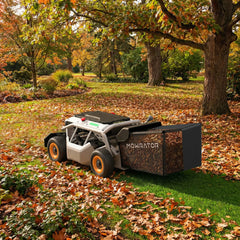 A Mowrator robotic lawn mower with a large collection bag clears fallen brown leaves in a spacious autumn yard.