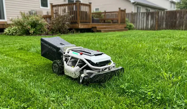 Mowrator robotic lawn mower on lush green grass near wooden deck and house